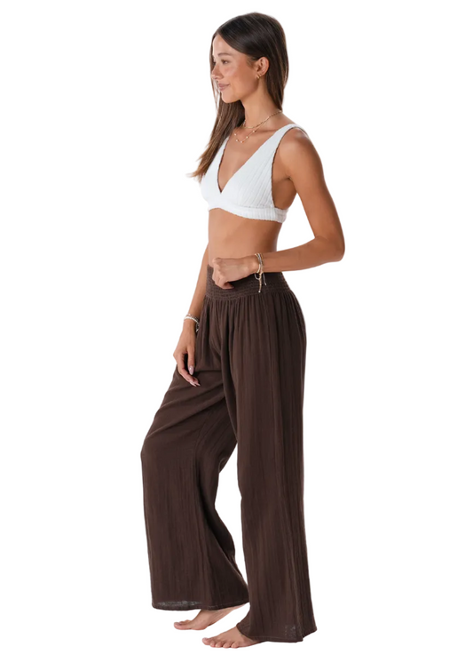 Woman wearing a white top and brown wide-leg pants on a white background