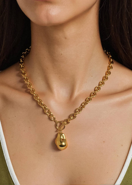 Gold chain necklace with a pendant worn by a person