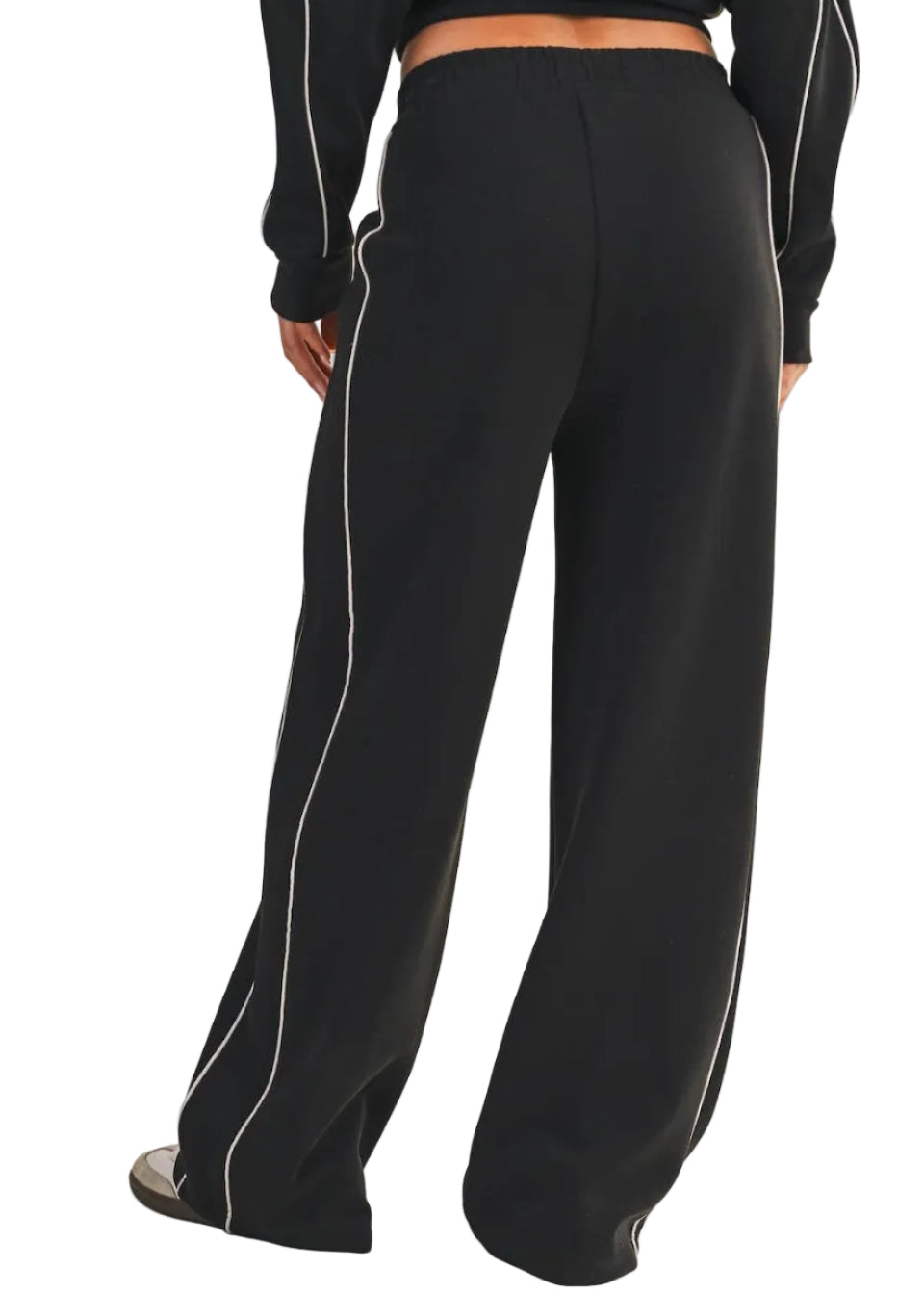Black pants with white piping on a beige background