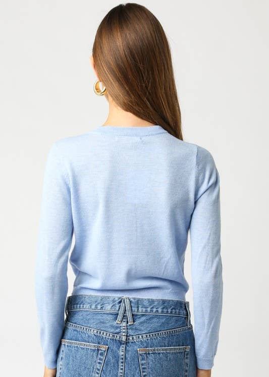 Person wearing a light blue sweater and blue jeans on a white background