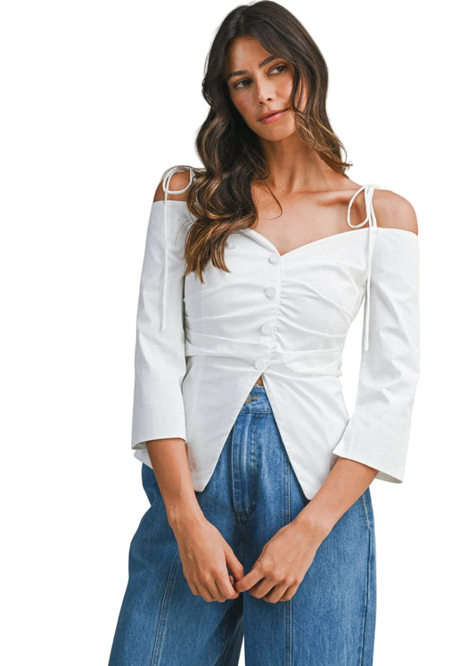 Woman wearing a white blouse with ruched design and blue jeans on a gray background