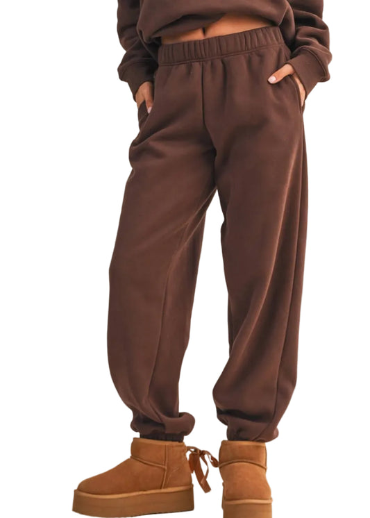 Brown sweatpants worn with brown platform boots on a beige background
