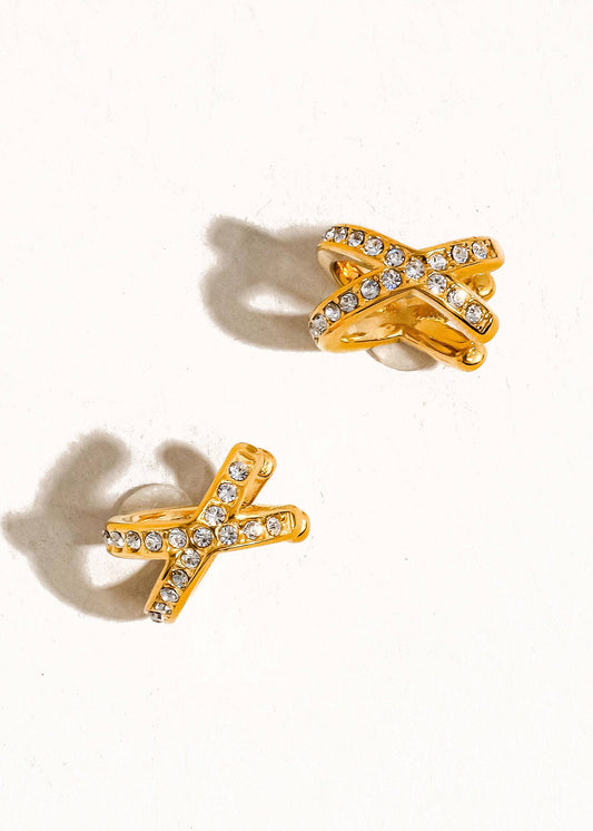 Gold bow-shaped earrings with clear gemstones on a white background