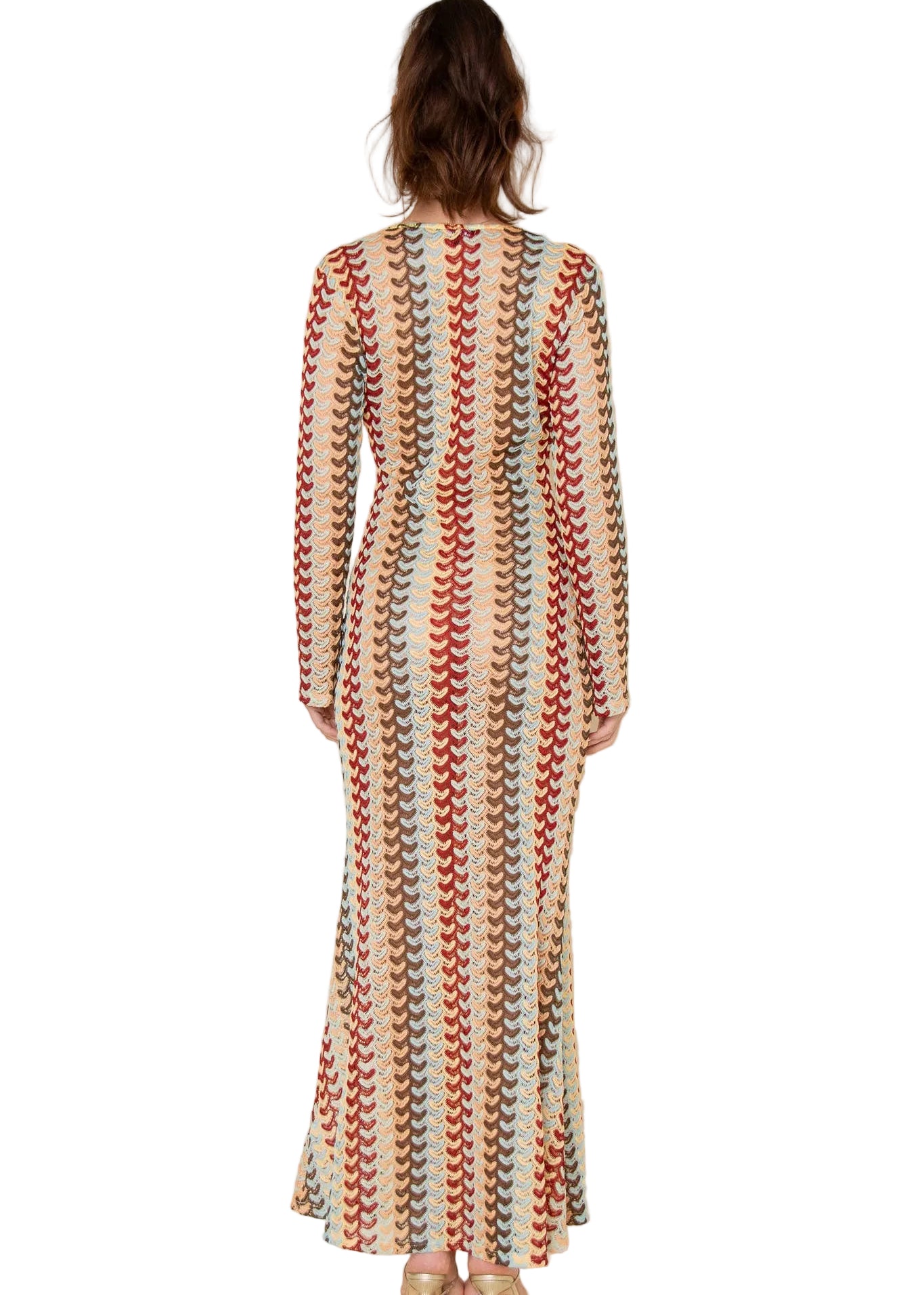 Woman wearing a long, patterned dress against a plain background