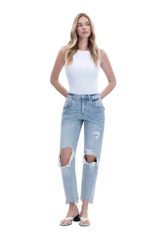Woman wearing a white top and light blue ripped jeans on a white background