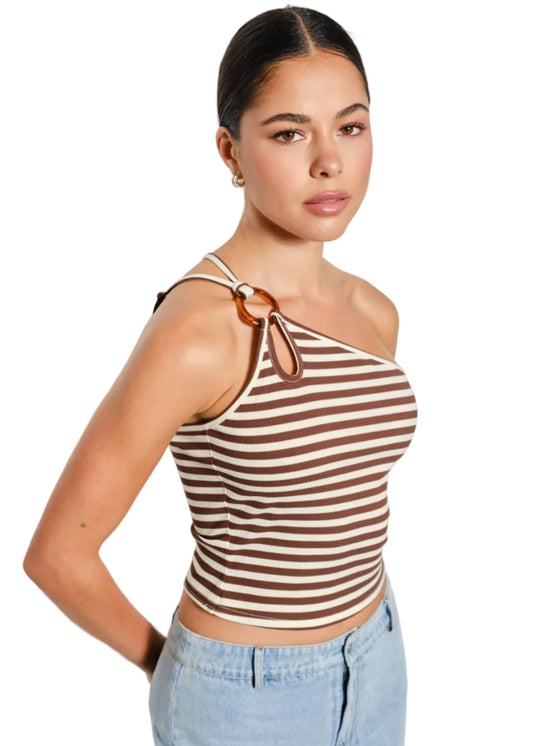 Woman wearing a brown and white striped tank top with light blue jeans against a plain background