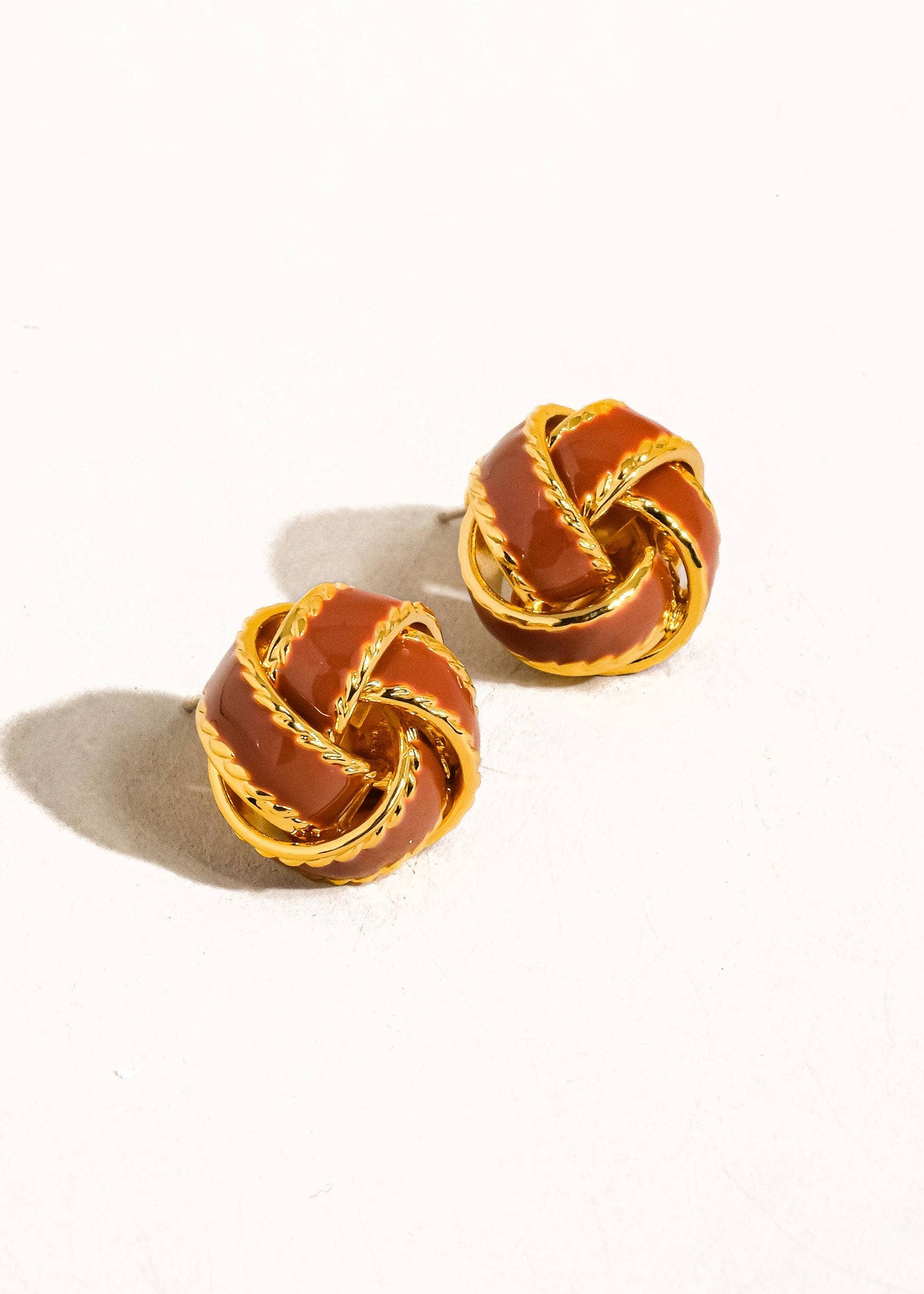 A pair of gold basket weaved ball stud earrings on a white background