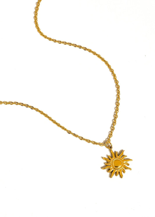 Gold necklace with a sun-shaped pendant on a white background