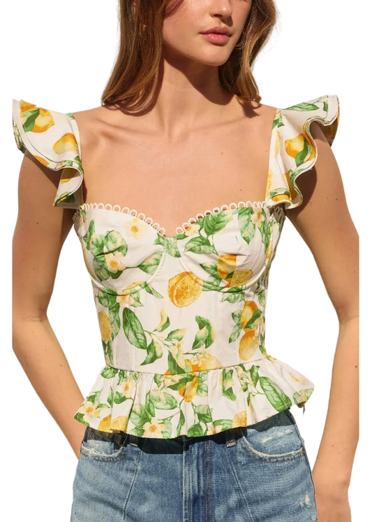 Woman wearing a floral top with lemon design against a neutral background