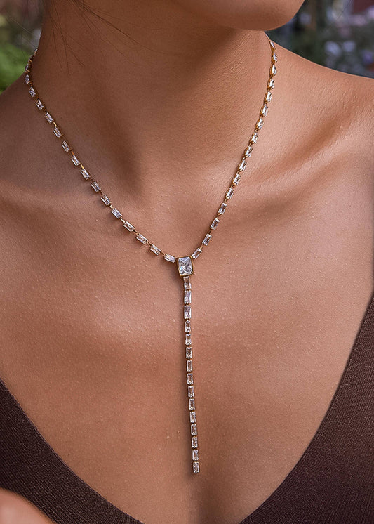 Necklace with a diamond pendant on a person wearing a brown top.