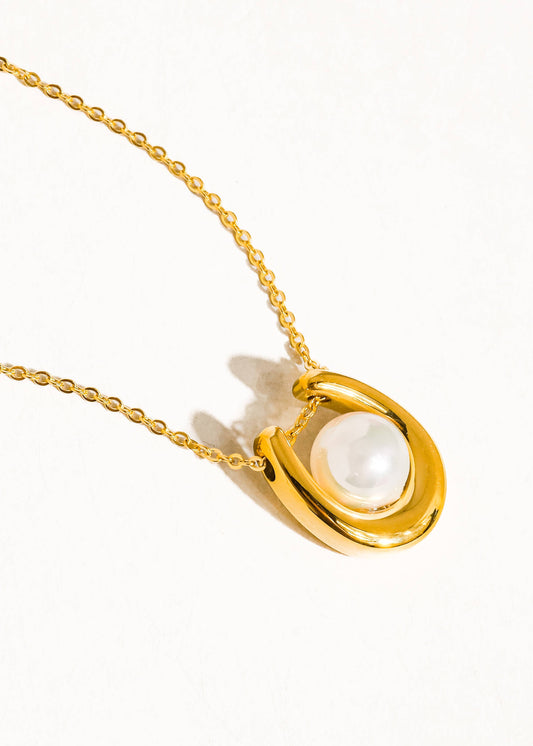 Gold necklace with a pearl pendant on a white background