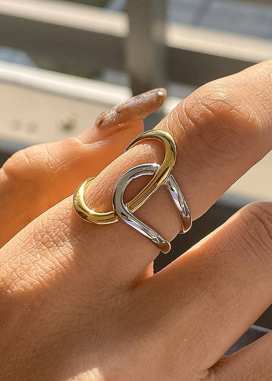 Hand wearing a gold and silver ring with blurred background