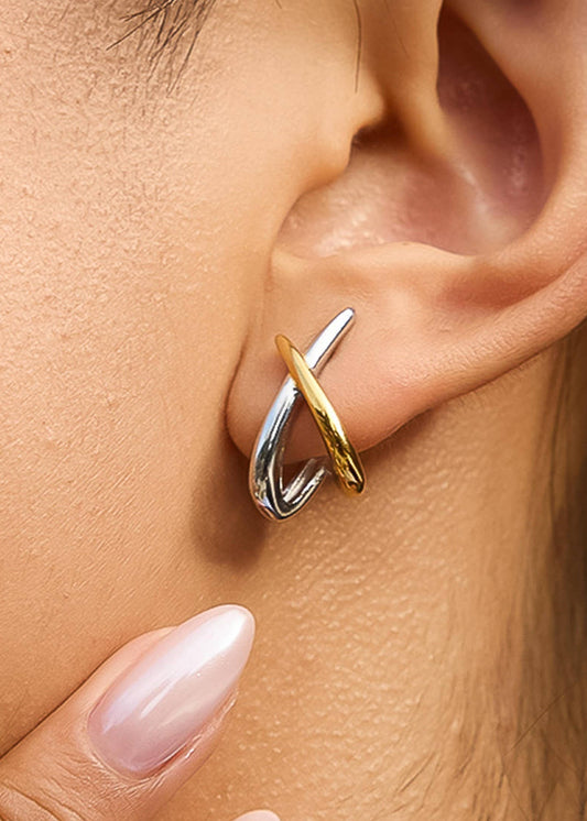 Close-up of a gold and silver earring worn on an ear.