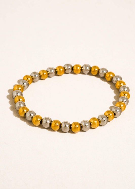 Beaded bracelet with yellow and silver beads on a beige background