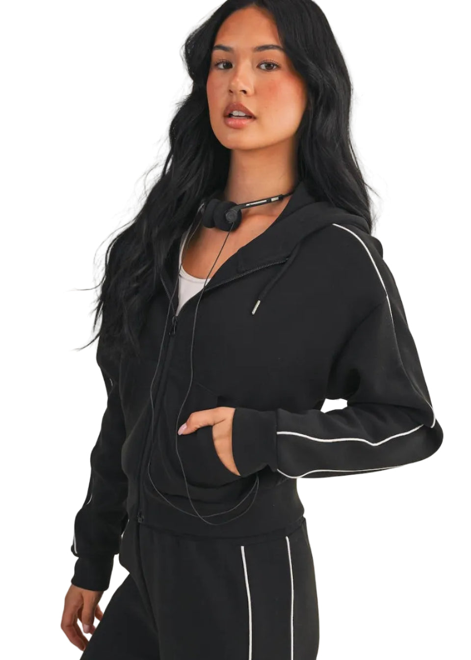 Woman wearing a black tracksuit with white piping on a beige background