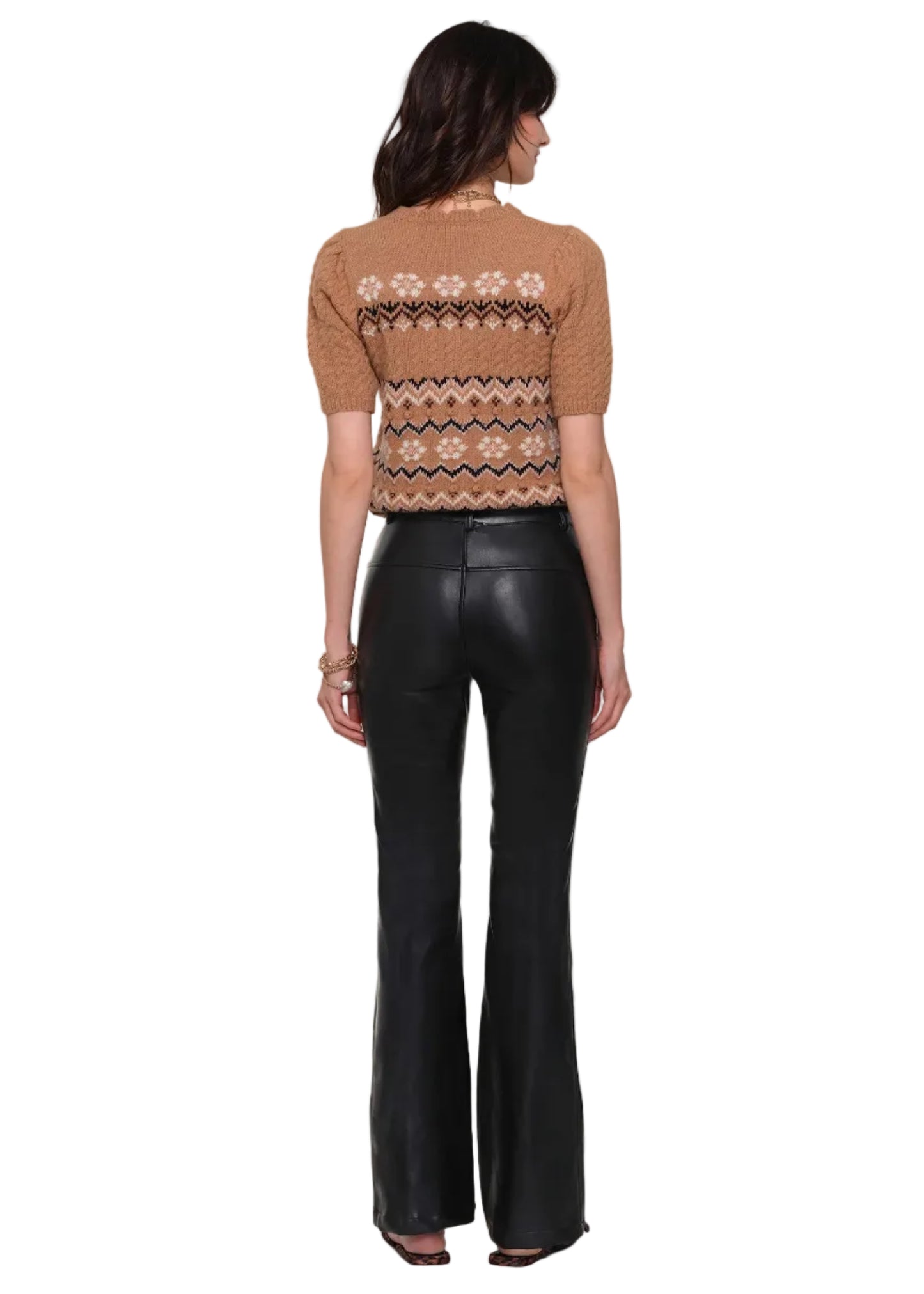 Person wearing a patterned brown top and black leather pants on a white background