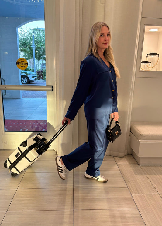 Woman pulling a suitcase into a building with a car visible outside.