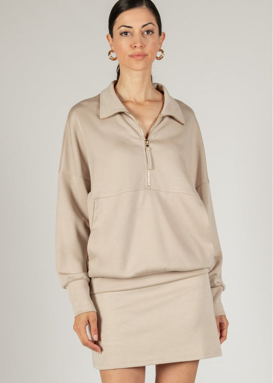 A woman wearing a beige mini skort with a button-up front and earrings.