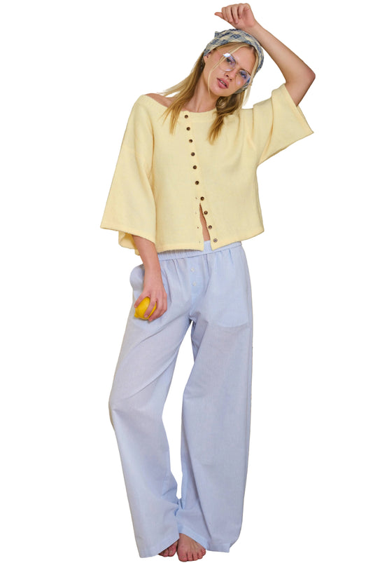 Woman in a yellow cardigan and light blue pants standing in a room