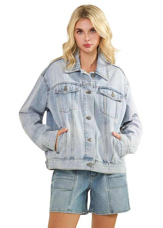 Woman wearing a light blue denim jacket and shorts on a beige background