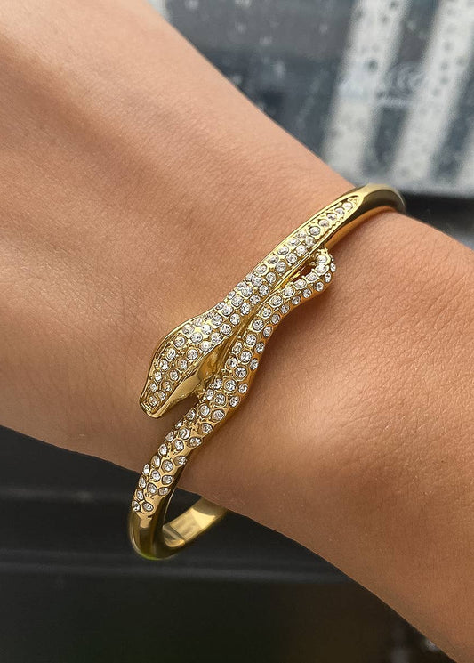 Gold bracelet with rhinestones on a wrist against a blurred background