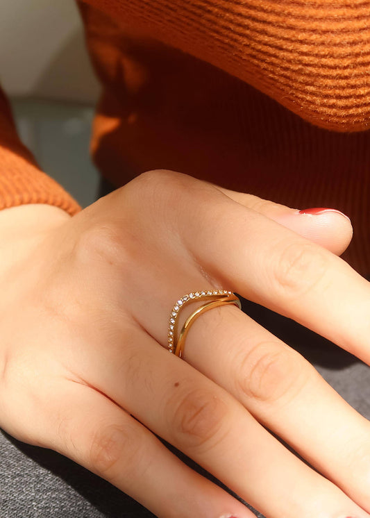 Close-up of a hand wearing a gold ring with a blurred background