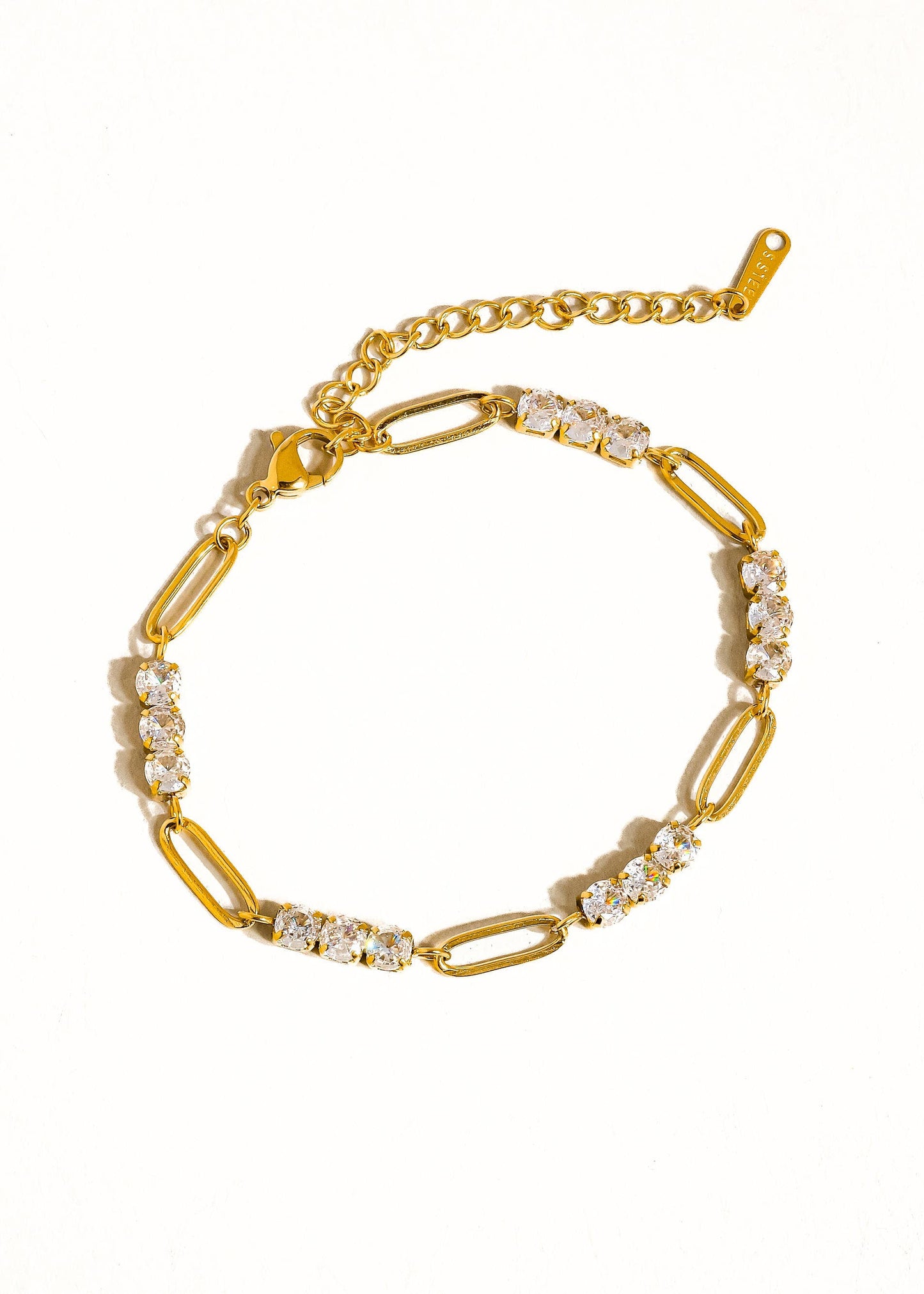 Gold bracelet with clear stones on a white background