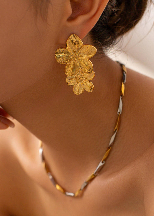 A person wearing a gold-colored floral earring