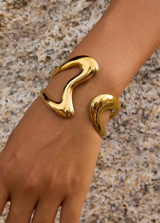 Gold bracelet on a wrist against a textured surface