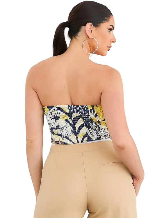 Woman wearing a strapless top with a colorful pattern and beige pants against a white background