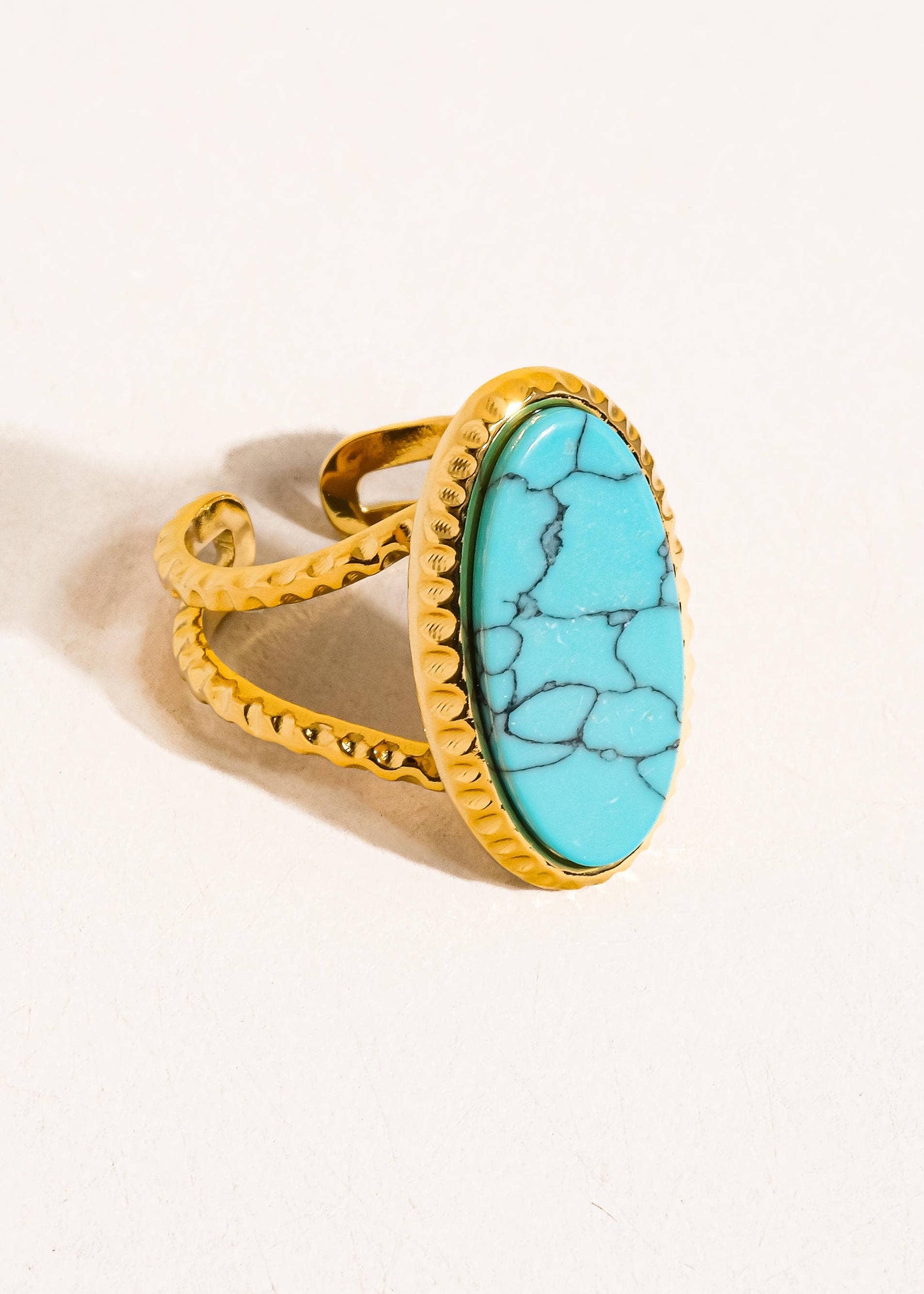 Gold ring with a turquoise stone on a light background