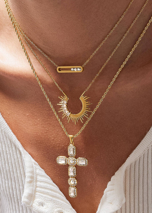 Close-up of a person wearing multiple gold necklaces with pendants.