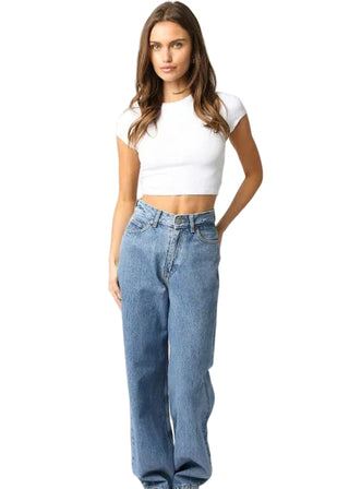 Woman wearing a white crop top and blue jeans on a white background