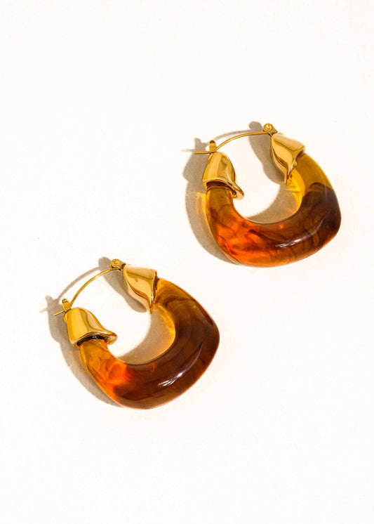 Pair of gold hoop earrings with amber-colored stones on a white background