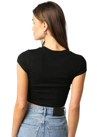 Person wearing a black crop top and blue jeans on a plain background