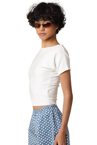 Woman wearing a white crop top and blue polka dot pants against a beige background