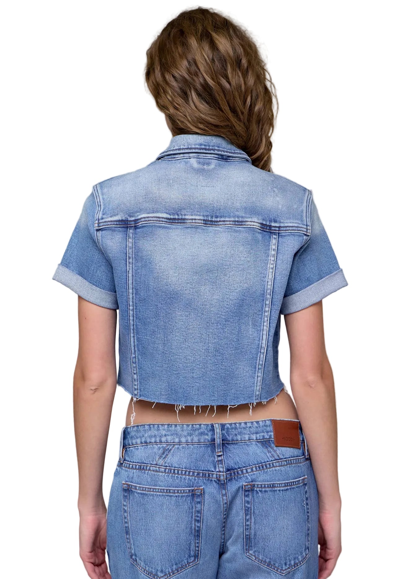 Person wearing a denim jacket and jeans on a gray background