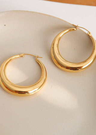 Gold hoop earrings on a beige surface