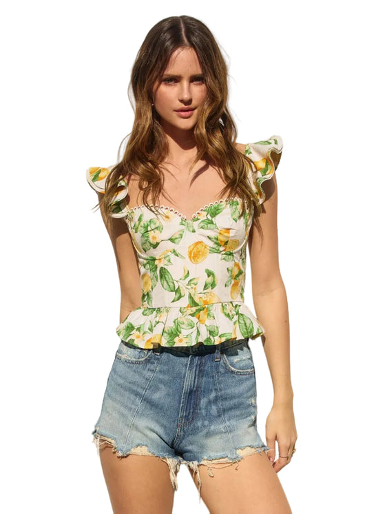 Woman wearing a floral top and denim shorts against a plain background