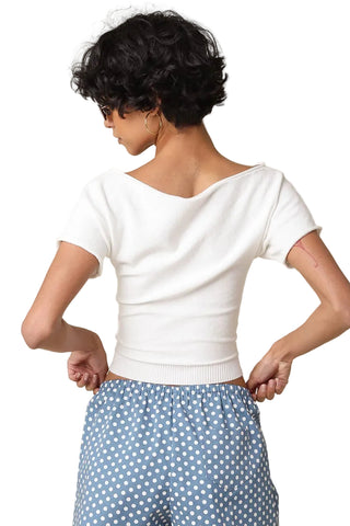 Person wearing a white top and blue polka dot pants on a beige background