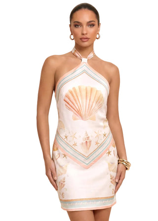 Woman wearing a dress with shell and starfish patterns on a beige background