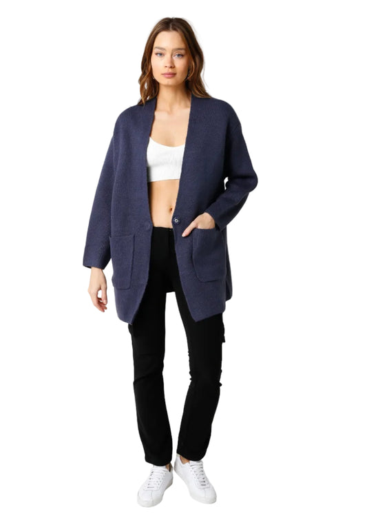 Woman wearing a navy blazer, white top, black pants, and white sneakers on a white background