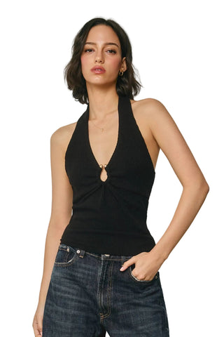 Woman wearing a black halter top and blue jeans against a plain background