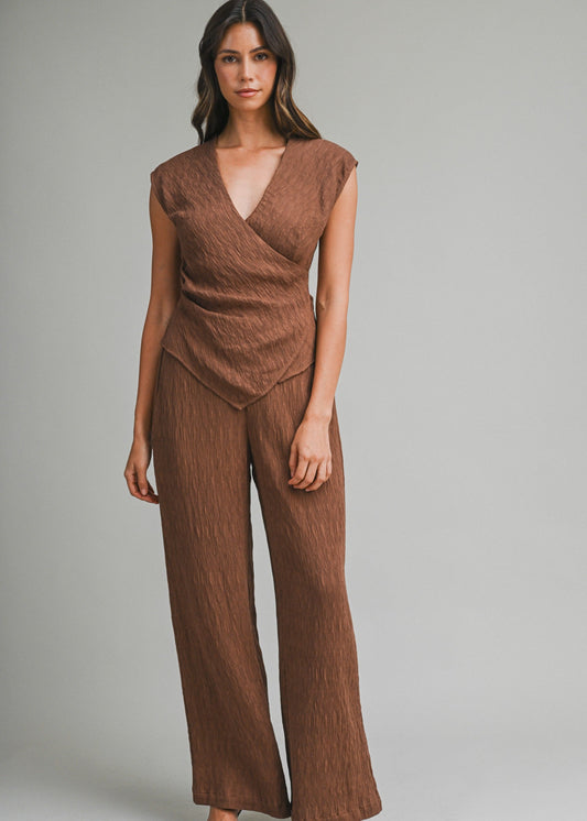 Woman wearing a brown textured top and pants set on a gray background