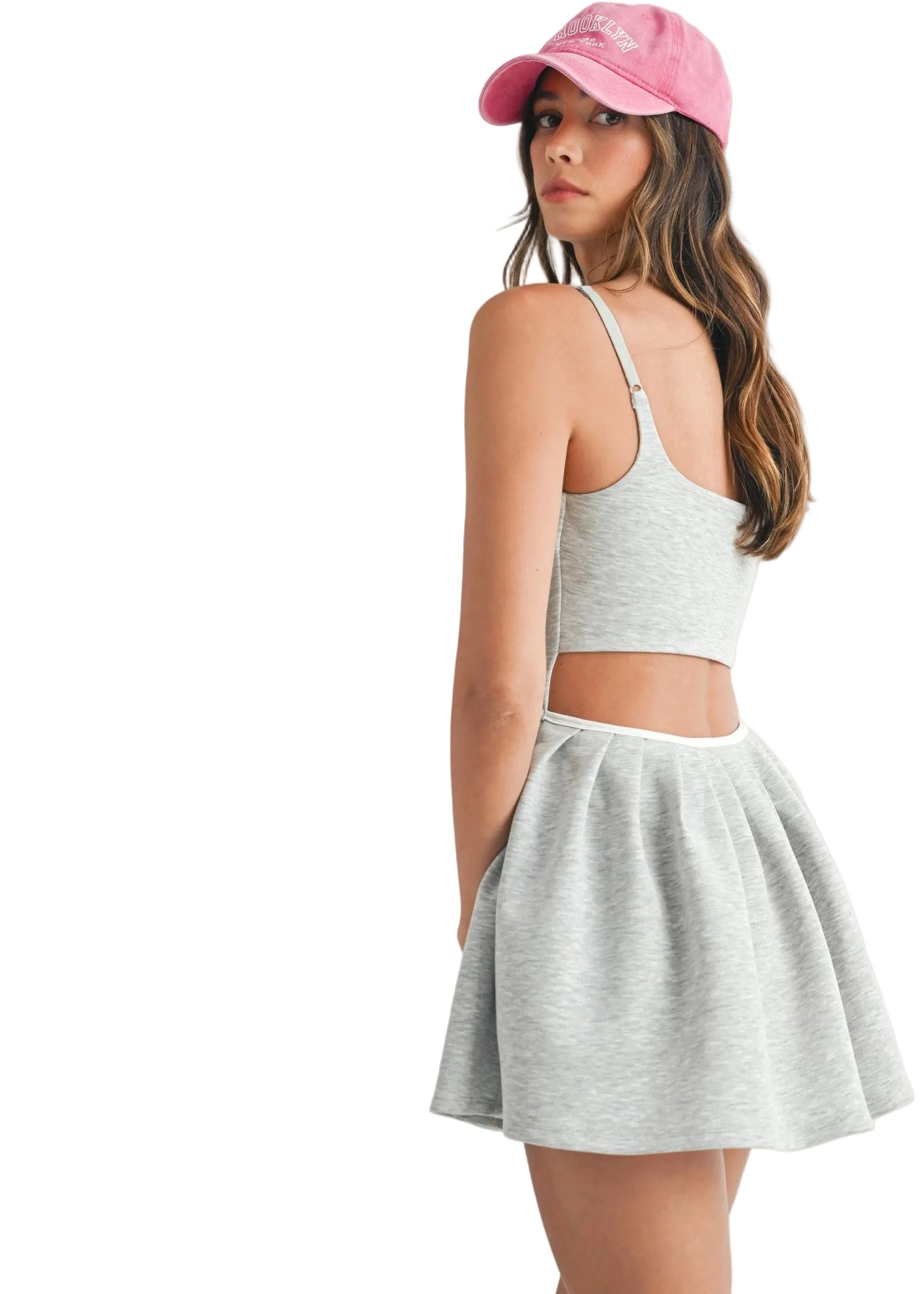 Woman wearing a gray tank top and skirt with a pink cap on a white background