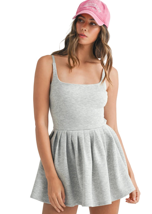 Woman wearing a gray active dress and pink cap on a beige background