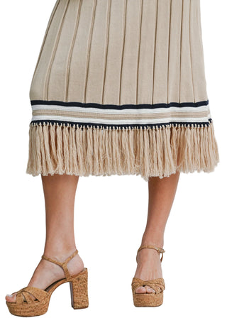 Beige pleated skirt with fringe details and cork platform sandals on a neutral background