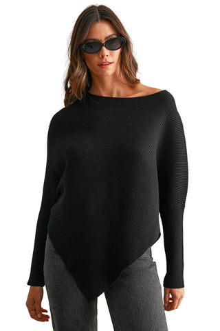 A woman modeling a black off-the-shoulder long-sleeve knit top with textured side panels, paired with gray pants, against a neutral beige background.