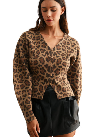 A woman wearing a cropped leopard-print cardigan with a V-neck and front buttons, paired with a black mini skirt, against a plain beige studio background.