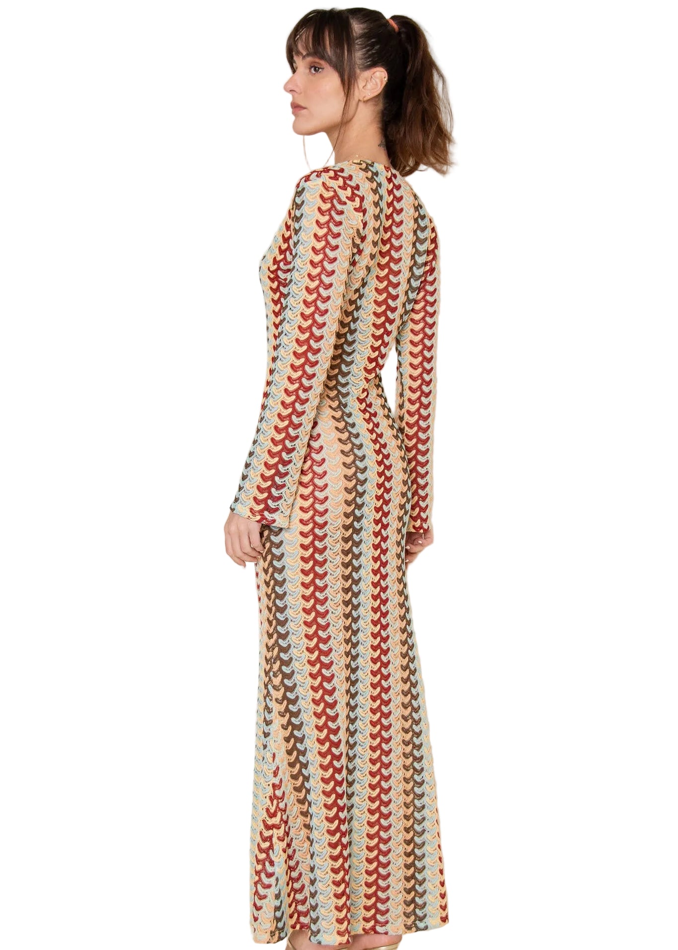 Woman wearing a long, patterned dress against a plain background
